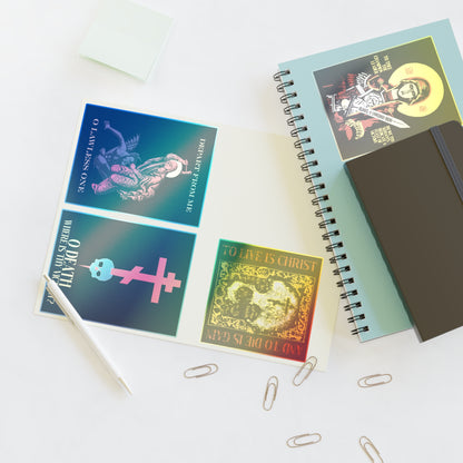 Open notebook with colorful religious-themed cards, Bestseller Mix No. 1 Four Orthodox Stickers (featuring Theotokos Champion Leader, St Marina, Death Where is Thy Victory, and To Live is Christ), pen, sticky notes, and paper clips on a white desk.