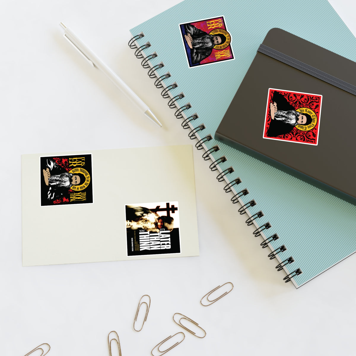 Two notebooks, a pen, clips, and Fr Seraphim Rose Four Sticker Sheet No. 1 are neatly arranged on a desk.