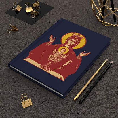 A navy blue Orthodox Christian blank journal featuring the Holy Theotokos IconoGraphic of the Inexhaustible Chalice, Deliverer from Addictions and Conqueror of Passions, displayed on a brown desk with stationery.