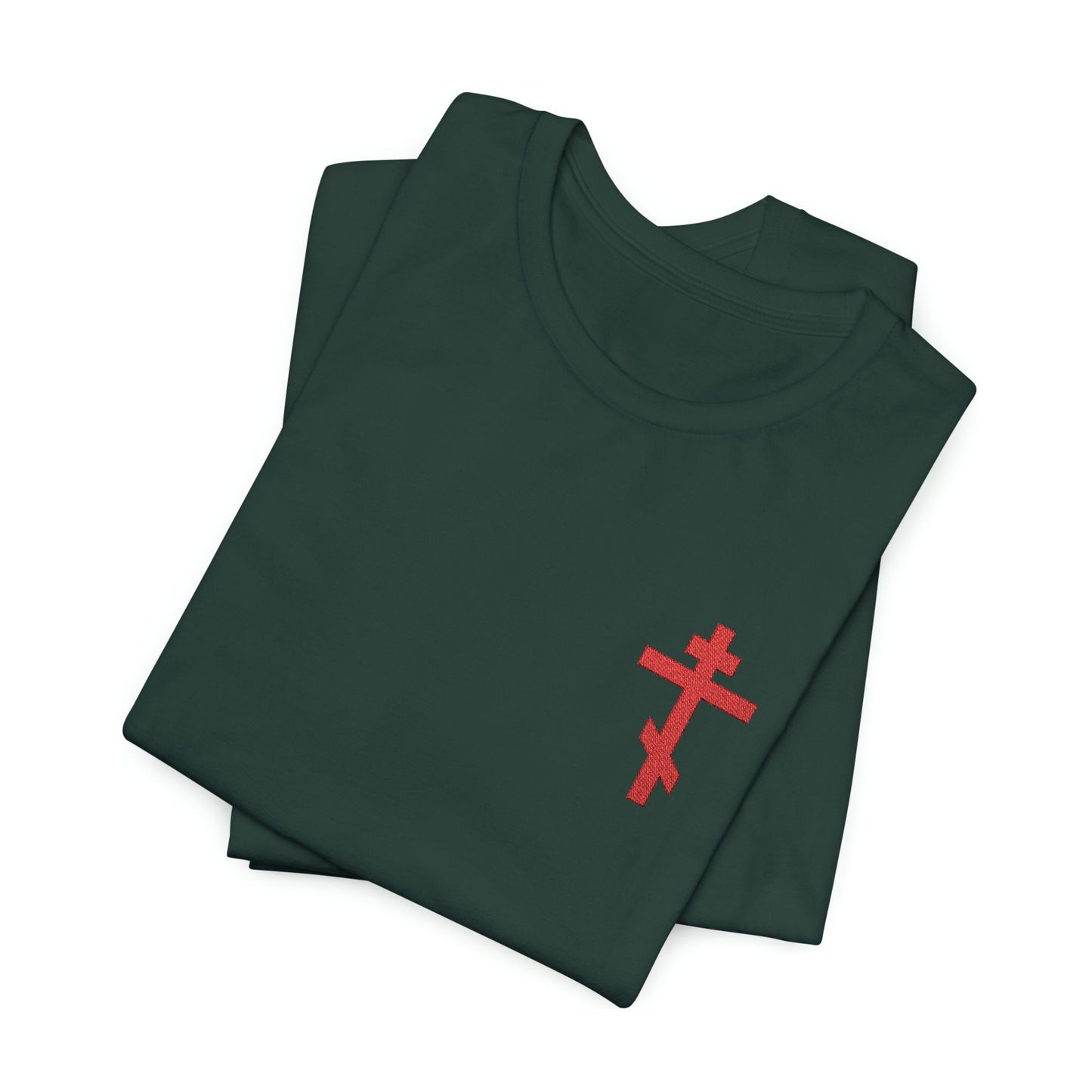 Two folded dark green cotton unisex t-shirts feature a small red embroidered Orthodox cross on the chest, inspired by Galatians 6:14—“May I Never Boast Except in the Cross.”.