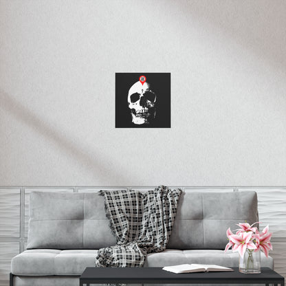 A gray couch with a plaid blanket, a pink flower vase, and the "You Will Be Here Maps Marker on Skull Design" Orthodox Christian art poster above—a memento mori echoing St Ignatius Brianchaninov’s teachings.