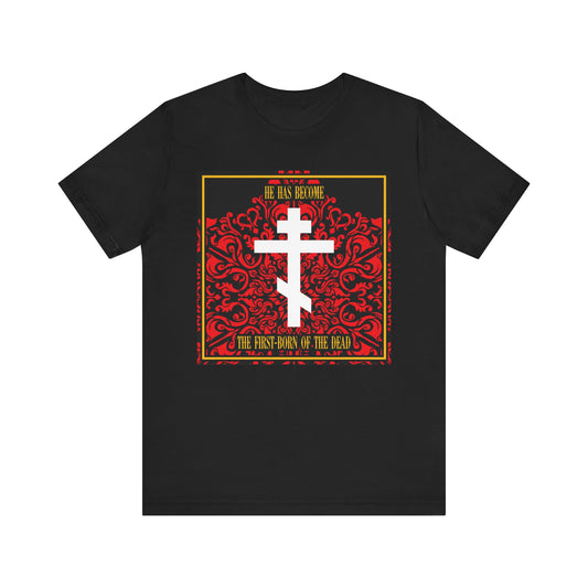 Black lightweight cotton unisex tee featuring a white Orthodox cross on a red floral texture; text reads "He Has Become the First-Born of the Dead," referencing Jesus Christ, the faithful witness.