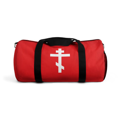 Red gym duffel bag with black handles, adorned with a white Orthodox cross on a red background and the Galatians 6:14 quote: "May I never boast, except in the cross of our Lord Jesus Christ." Orthodox Christian design.