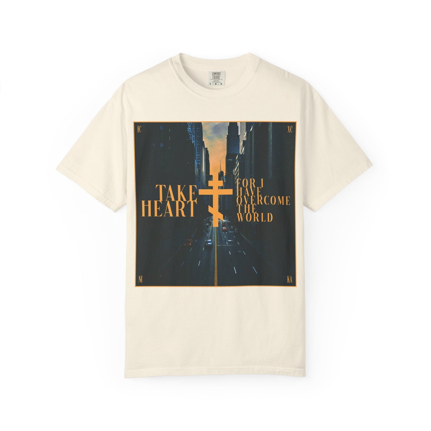 Ivory heavyweight cotton unisex tee featuring a modern city street scene and the phrase “Take Heart, For I Have Overcome the World (John 16:33)” in gold—an inspiring design reflecting the promise of sorrow turned into joy.