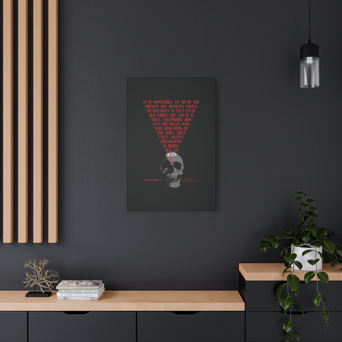 A dark room features "The Present Day As the Last Day of Our Life | St John Climacus | Skull with Red Orthodox Cross" Orthodox canvas wall art above a black cabinet decorated with books, a bonsai, and a plant.