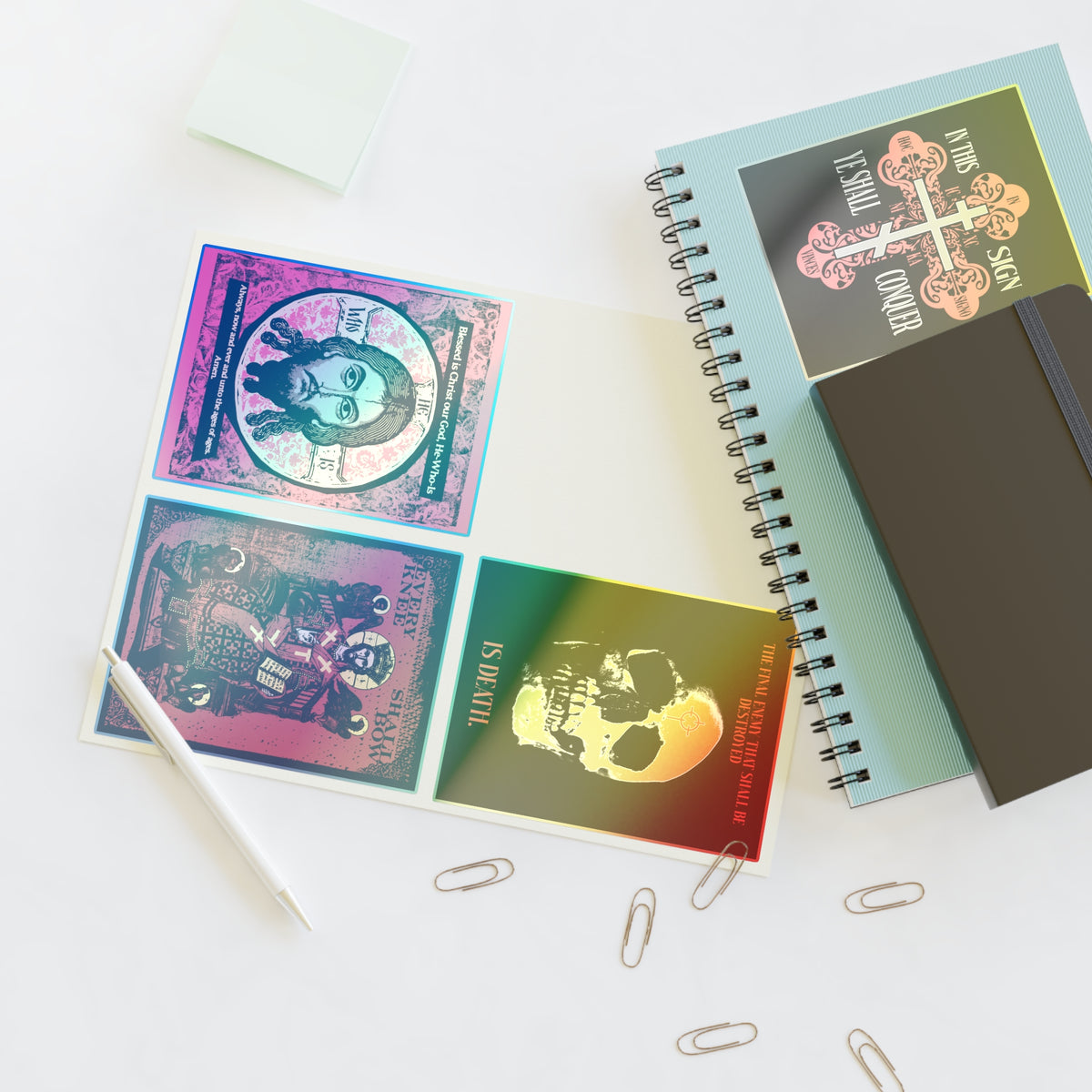Bestseller Orthodox Sticker Mix No. 3 on desk with pen, spiral notebook, sticky notes, and paperclips.