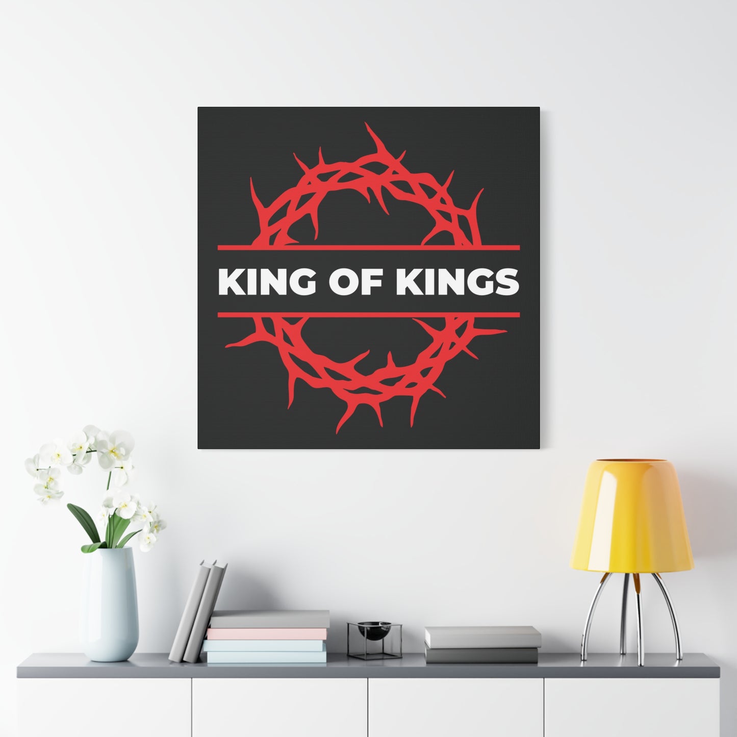 King of Kings Crown of Thorns | The King of Glory canvas art, inspired by Revelation 19:16, features bold "Christ is King" text and depicts the red crown of thorns—perfect above a white console table and yellow lamp.