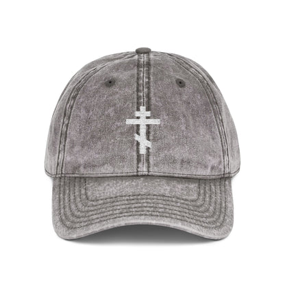 Charcoal grey distressed cap featuring a simple white Orthodox TriBar cross embroidered on the front, symbolizing crucifixion and personal humility. Minimalist Christian design: "Crucify My Ego to the Precious and Life Giving Cross.