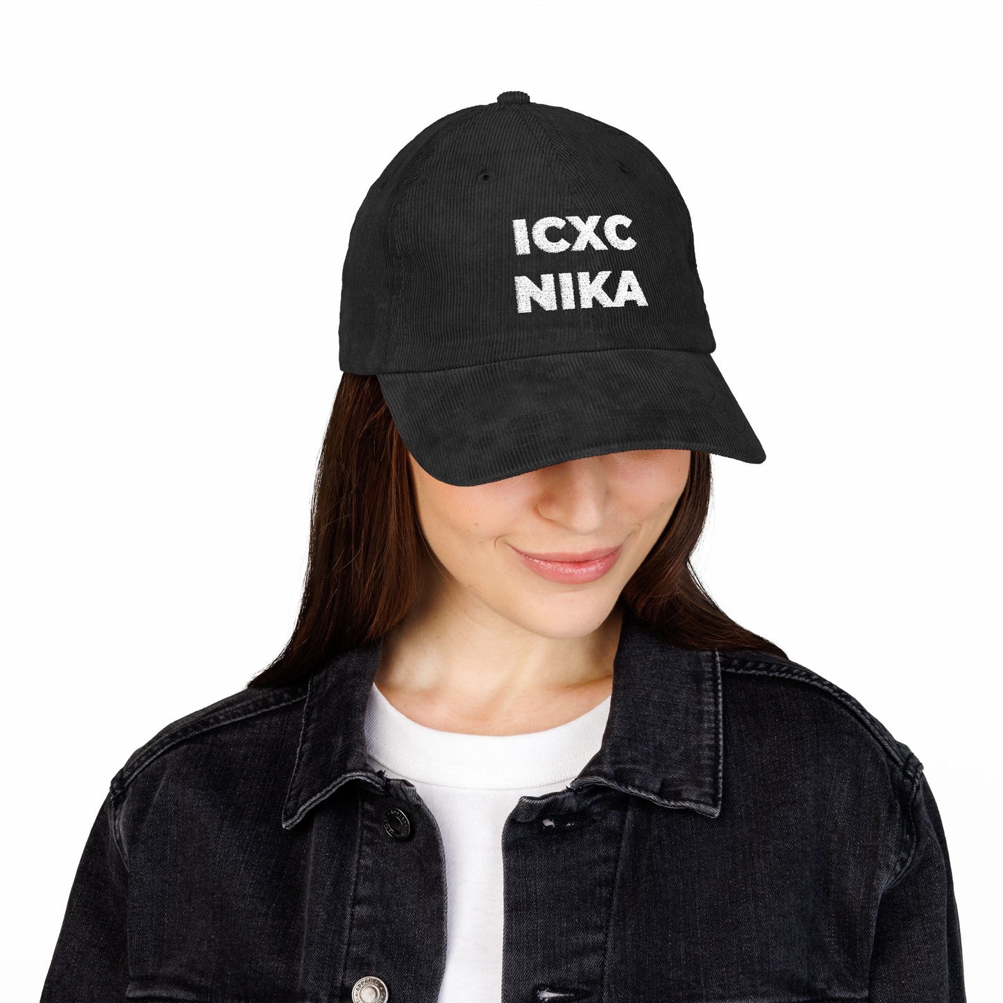 A woman wears a White ICXC NIKA Text Christogram embroidered cotton corduroy cap, symbolizing "Jesus Christ Conquers," paired with a black denim jacket.