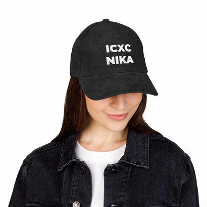 A woman wears a White ICXC NIKA Text Christogram embroidered cotton corduroy cap, symbolizing "Jesus Christ Conquers," paired with a black denim jacket.