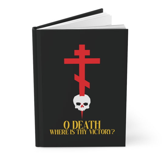 A black hardcover journal titled "O Death Where is Thy Victory? (1 Corinthians 15:55)" features a red Orthodox cross stabbing a white skull with yellow text—an Orthodox Christian accessory reflecting on the Resurrection.