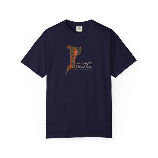 True navy heavyweight cotton unisex tee featuring an illuminated manuscript-inspired ornate letter P and cursive text, drawing inspiration from Abba Agathon’s teaching that “prayer is warfare to the last breath”—a subtle tribute to spiritual discipline in the tradition of the Desert Fathers.