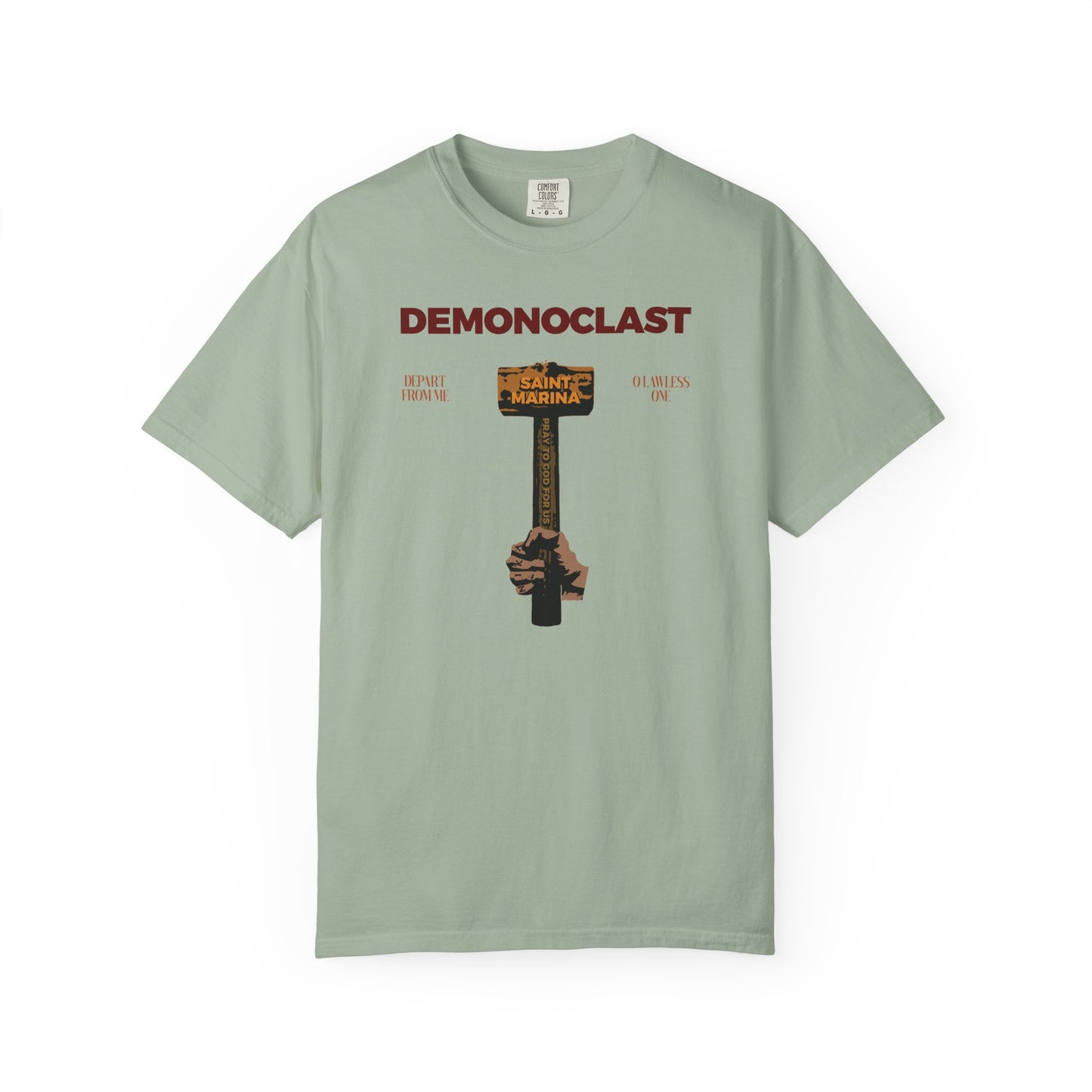 Bay heavyweight cotton unisex tee featuring DEMONOCLAST text and an illustrated NIKA fist holding St. Marina's Hammer, inspired by Orthodox themes of Christ Conquers, unseen warfare, and martyrdom.