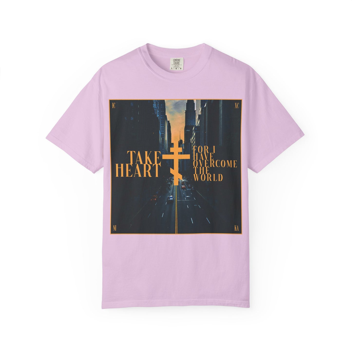 Orchid-colored heavyweight cotton unisex tee featuring a modern city street scene and bold gold text: "Take Heart, For I Have Overcome the World (John 16:33)." This design serves as a reminder that even when sorrow turns to joy, these redemptive words remain true.