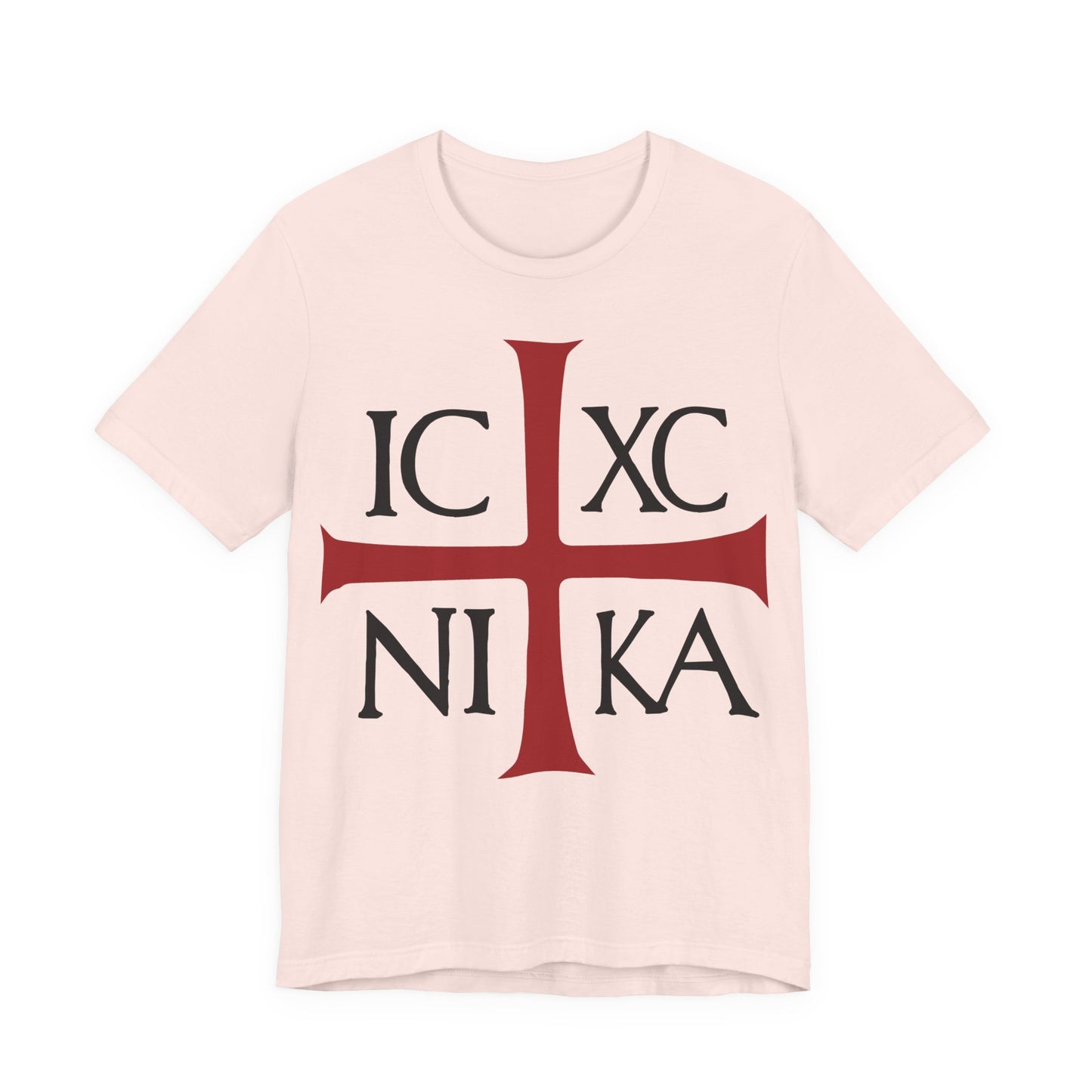 A soft pink cotton T-shirt featuring a red cross and black IC XC NI KA text, inspired by ancient Byzantine Christograms—"Jesus Christ Conquers"—as worn in Orthodox Christian tradition.