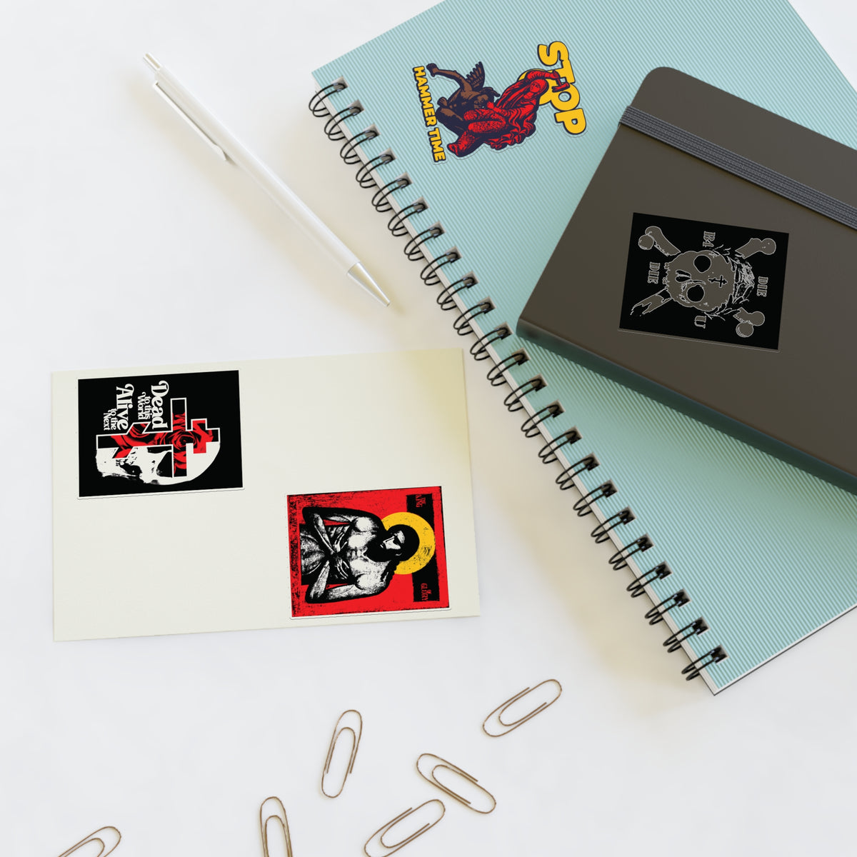 Two notebooks, a pen, and Random Mix No. 1 Four Sticker Sheet on a white table.