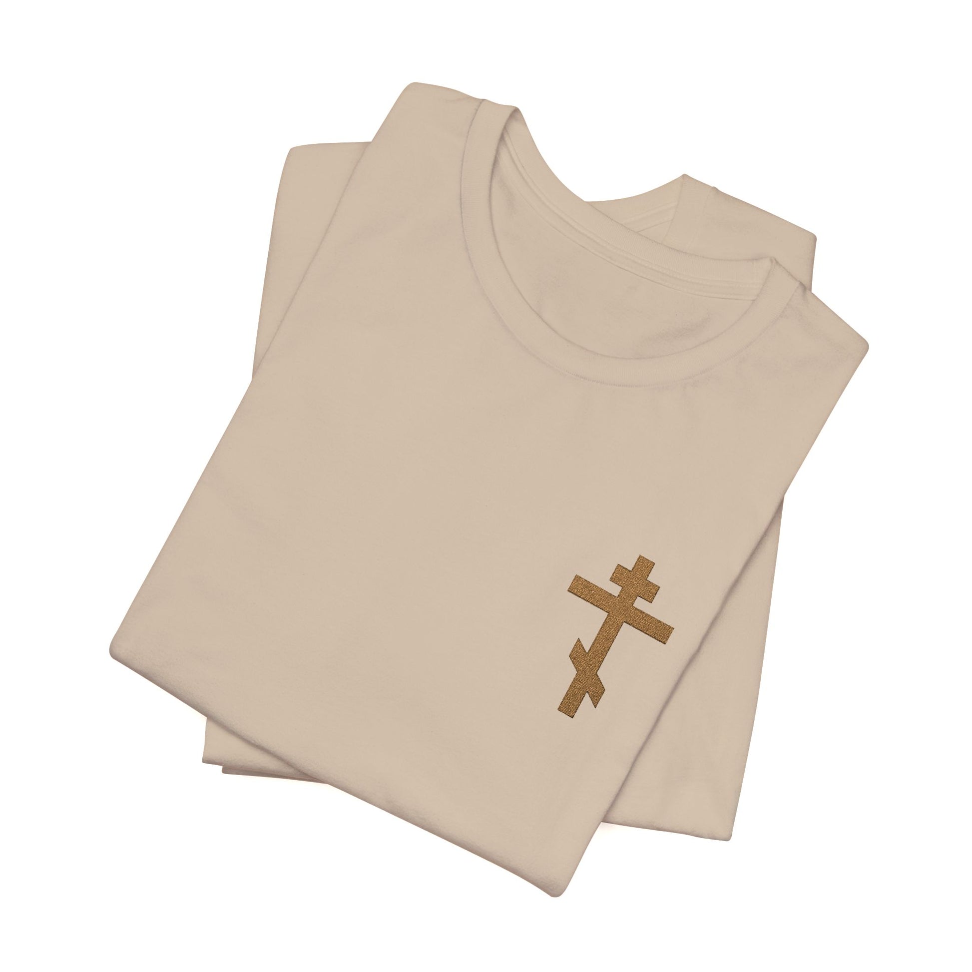 Two folded beige "Small Embroidered Orthodox Cross" earthtone t-shirts, featuring a subtle brown cross on the front left, inspired by Galatians 6:14: “May I Never Boast Except in the Cross.” Christian cotton unisex design.