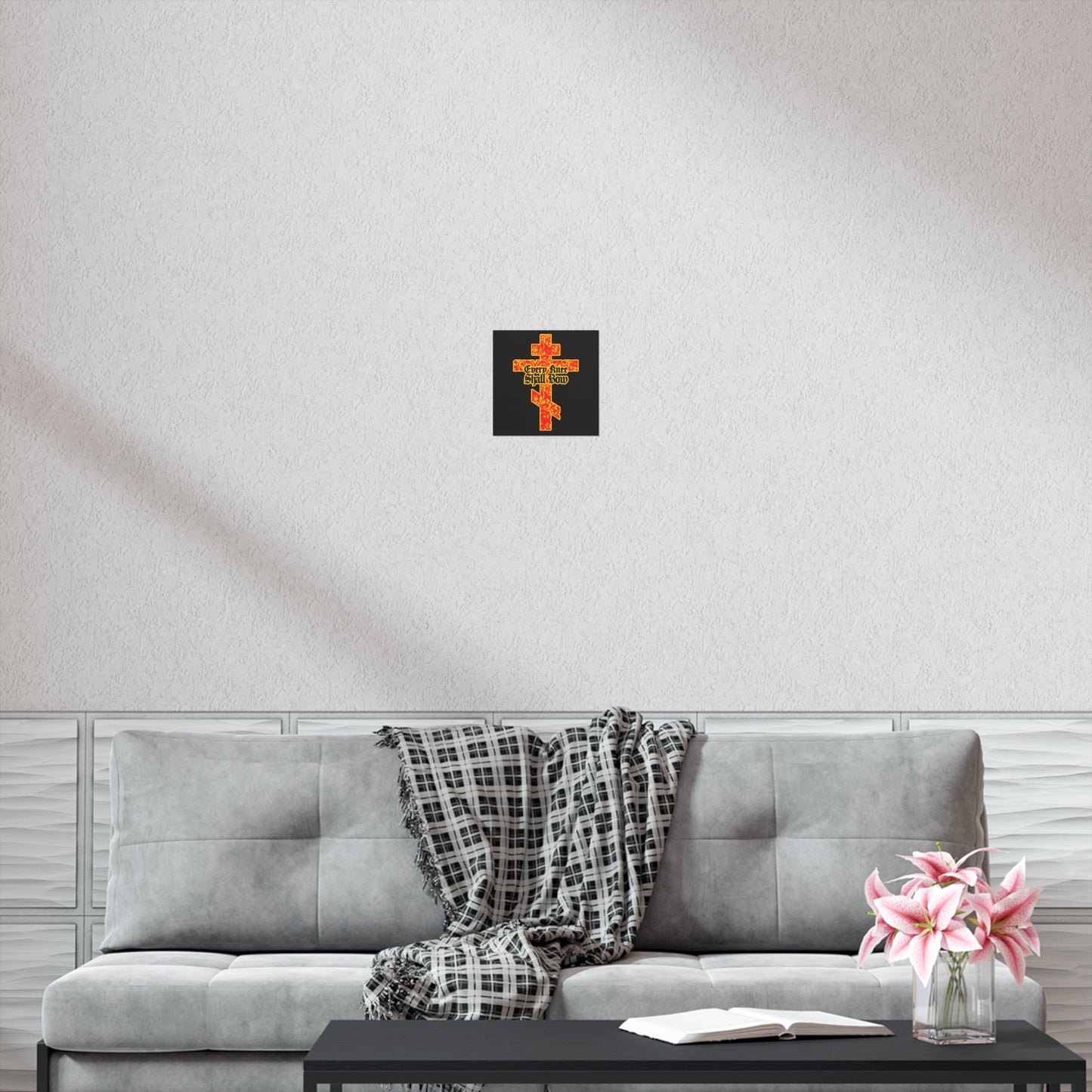 A gray sofa with a plaid blanket, open book, pink flowers, and the "Every Knee Shall Bow" gold and red floral Orthodox cross poster above, creates a peaceful space reflecting righteousness and strength.
