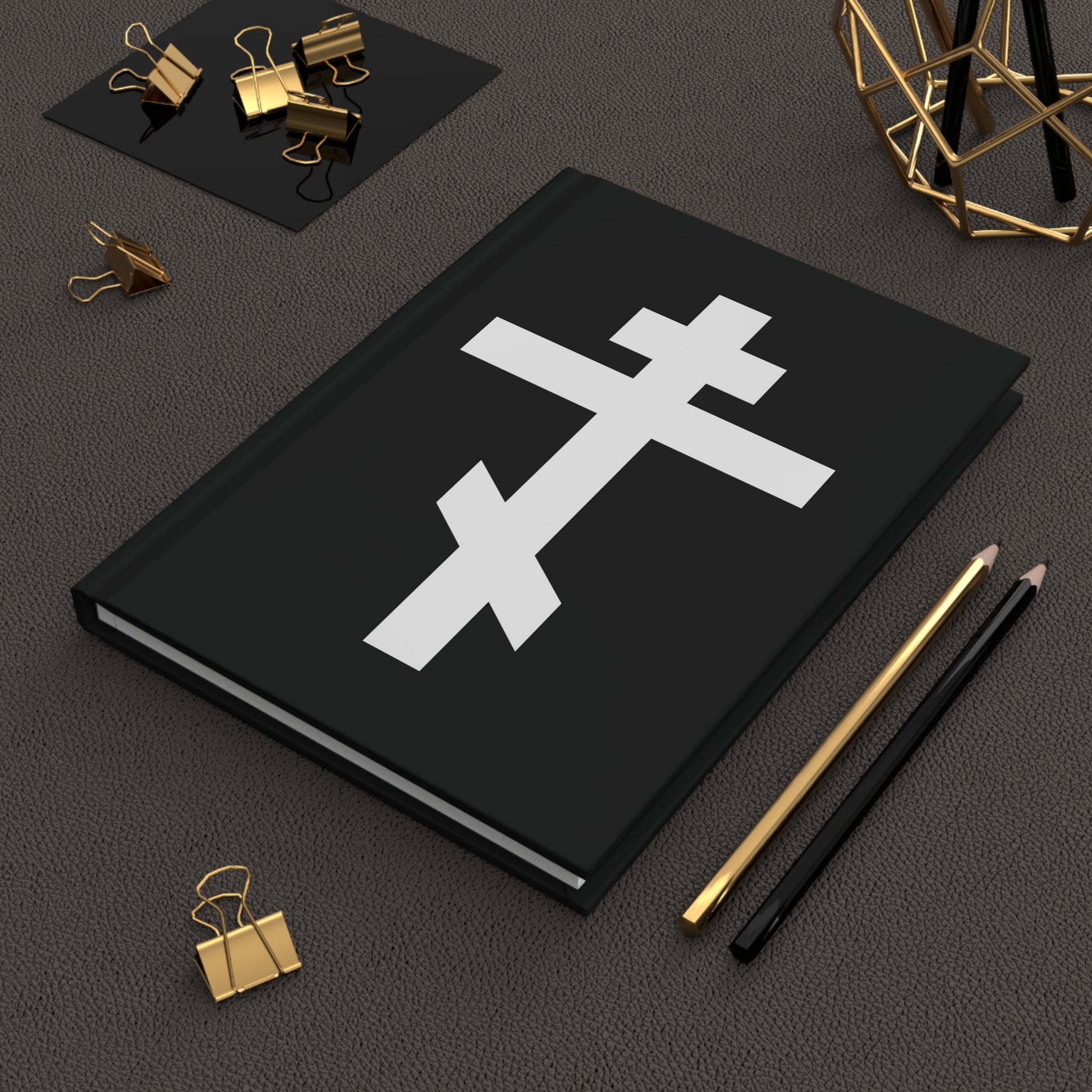 The "White Orthodox Cross | 'May I never boast, except in the cross of our Lord Jesus Christ' (Gal 6:14)" Orthodox Hardcover Journal features a white cross on a black cover, shown alongside gold clips and two pencils.