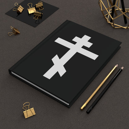 The "White Orthodox Cross | 'May I never boast, except in the cross of our Lord Jesus Christ' (Gal 6:14)" Orthodox Hardcover Journal features a white cross on a black cover, shown alongside gold clips and two pencils.