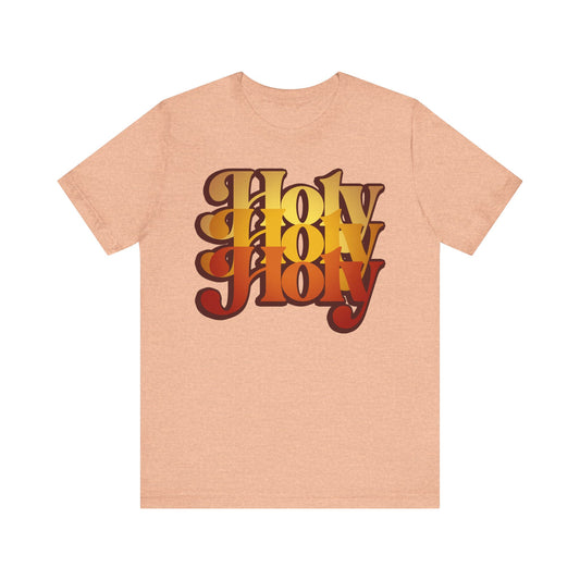 Heather peach unisex tee featuring bold “Holy Holy Holy” in retro 70s style, inspired by the Trisagion liturgical prayer from Isaiah 6 and the Cherubim & Seraphim, made of lightweight cotton.