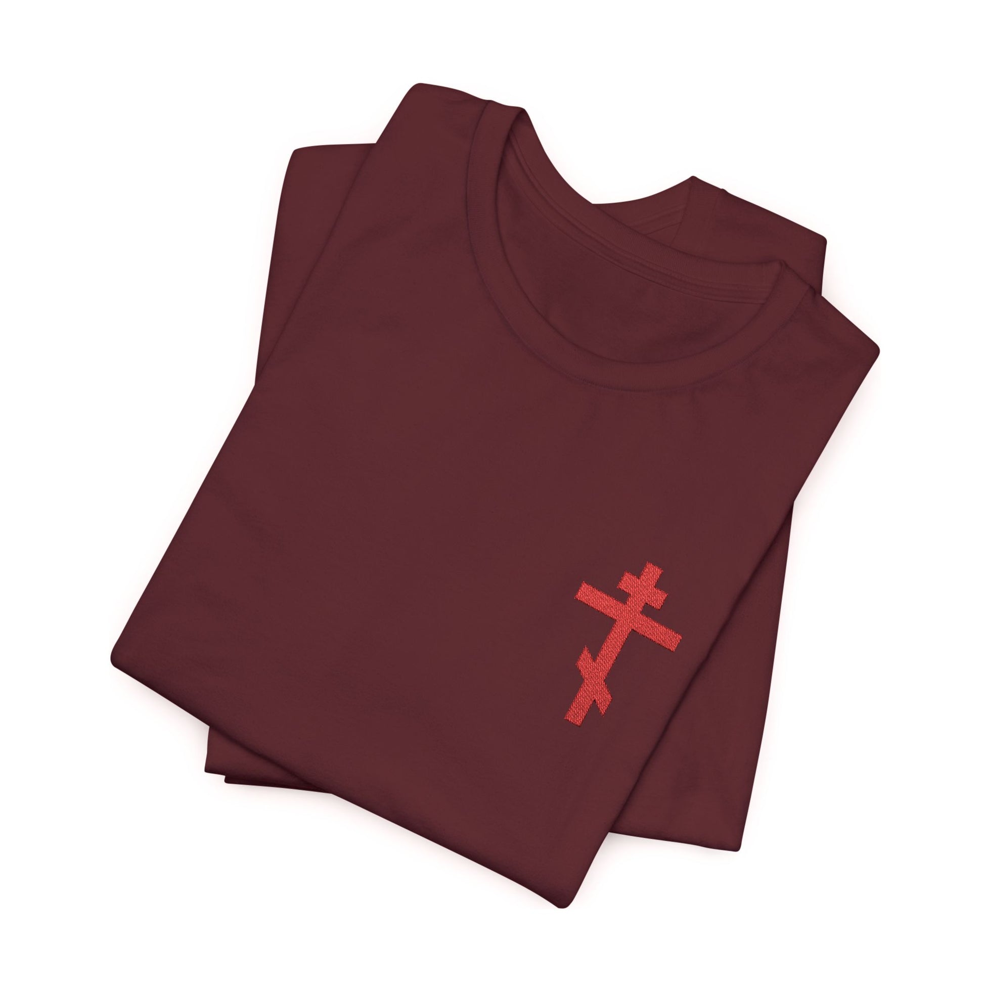 Folded maroon unisex cotton t-shirt featuring a small red embroidered Orthodox cross inspired by Galatians 6:14, displayed on a white background.