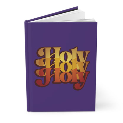 A purple hardcover journal titled "Holy Holy Holy Trisagion Liturgical Prayer" features bold, layered yellow and red retro text, inspired by Isaiah 6, with a 70s style and references to Cherubim & Seraphim prayers.