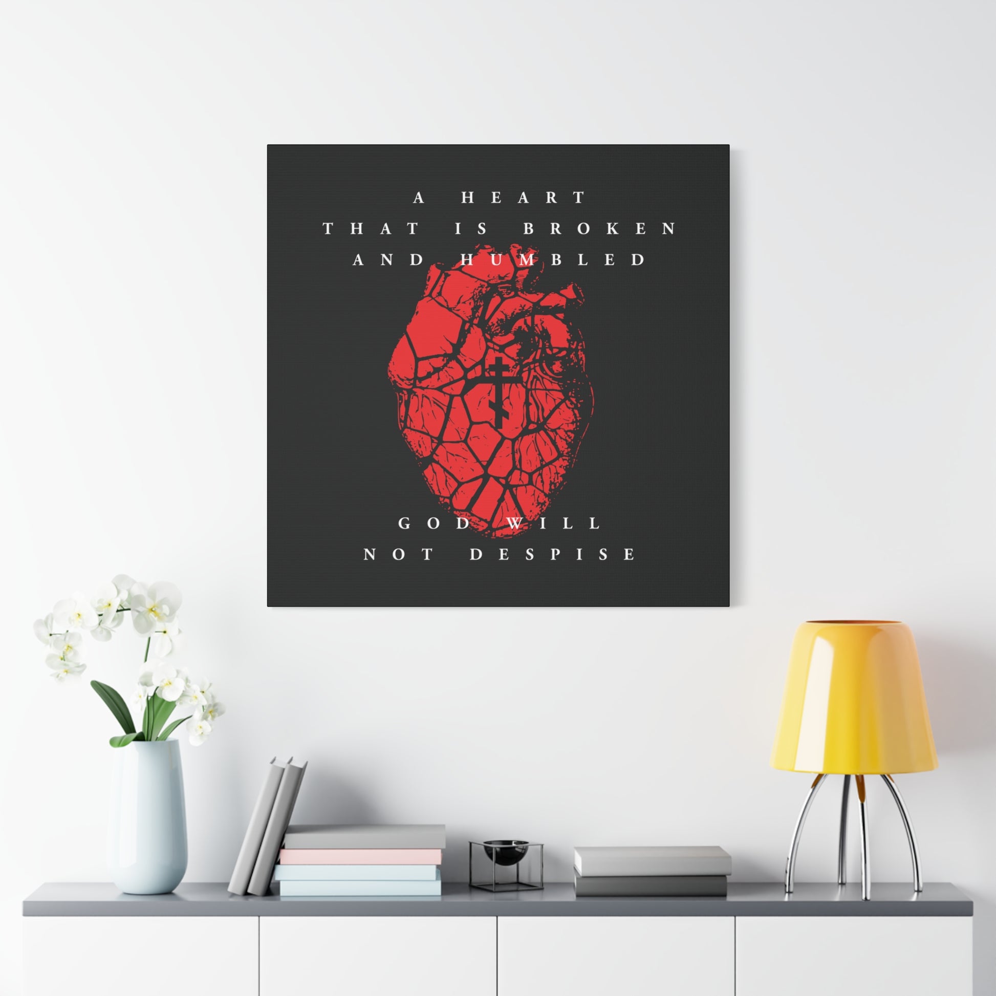 The "A Heart That is Broken and Humbled God Will Not Despise" canvas art, showing a cracked heart with an Orthodox cross, hangs above a shelf with decor, expressing repentance and inspired by Psalm 51.