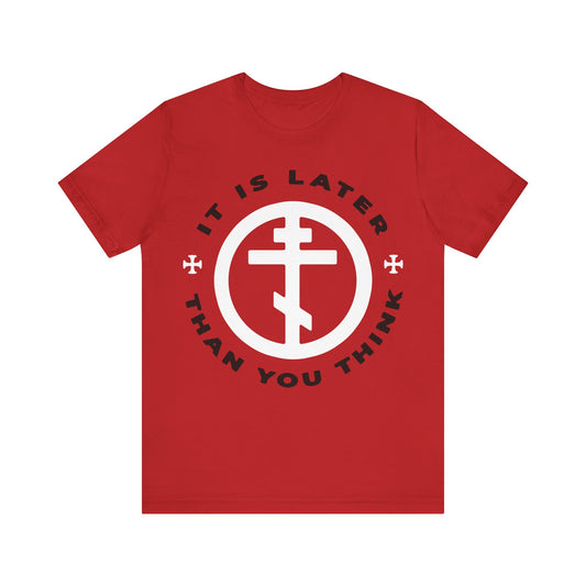 Red "It Is Later Than You Think" t-shirt inspired by Fr Seraphim Rose, featuring a white Orthodox cross in a circle and Memento Mori message. Christian apparel referencing Romans 13:10-12.