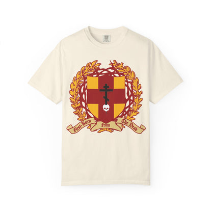 Ivory heavyweight cotton unisex t-shirt featuring a bold heraldic shield with an Orthodox cross piercing a skull, crowned with thorns, and laurel leaves, along with a banner reading “First-Born from the Dead (Col 1:18)”. This striking design is inspired by themes of redemption and sacrifice found in Exodus and Christian tradition.
