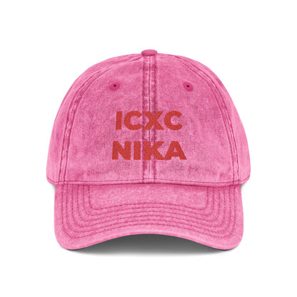 Pink distressed denim cap featuring red embroidered "ICXC NIKA" Christogram, meaning "Jesus Christ Conquers." Orthodox Christian symbol; Christ is King.