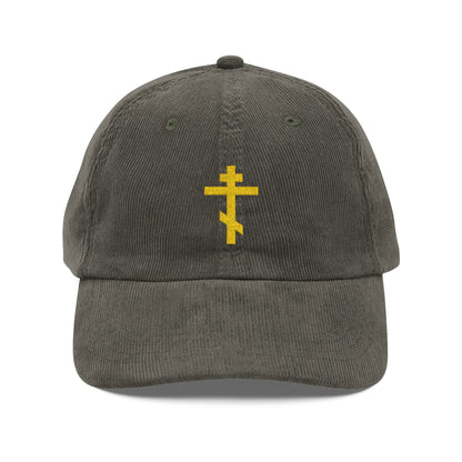 Olive corduroy cap featuring a yellow Orthodox TriBar Cross embroidery on the front, symbolizing the weapon of unseen warfare that makes demons tremble.