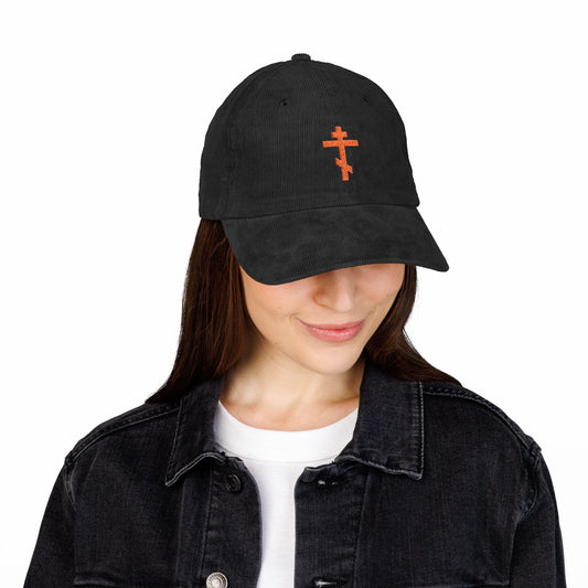 Woman in a Simple Red Orthodox TriBar Cross embroidered cotton corduroy cap, echoing Orthodox faith, paired with a black denim jacket and white shirt.