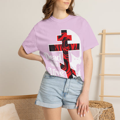 A woman in the "Dead to this World" Christian Goth flower cross & skull graphic T-shirt and denim shorts stands by a wicker chair and wooden rack indoors, showcasing the bestselling heavyweight cotton unisex tee.