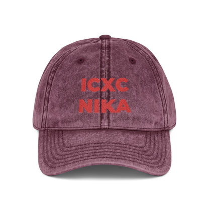 Maroon distressed denim cap embroidered with the red ICXC NIKA Greek Christogram—Orthodox Christian symbol meaning "Jesus Christ Conquers.