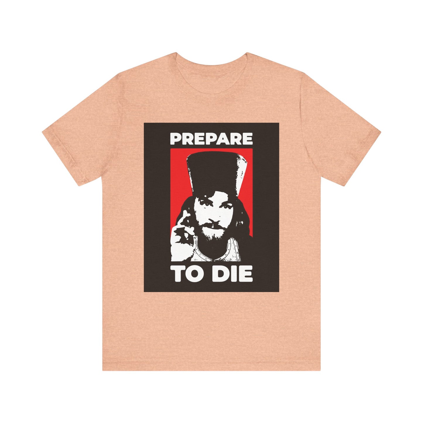 Heather peach t-shirt featuring a graphic of Inigo Montoya as an Orthodox priest giving a blessing, with the text "PREPARE TO DIE" on a black and red background—an evocative reminder to reflect on mortality, as echoed in the teachings of St. Hesychius.