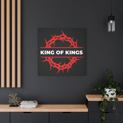 The "King of Kings Crown of Thorns | The King of Glory" Christian canvas art, inspired by Revelation 19:16, featuring a red crown and bold text, hangs on a dark wall above a desk.