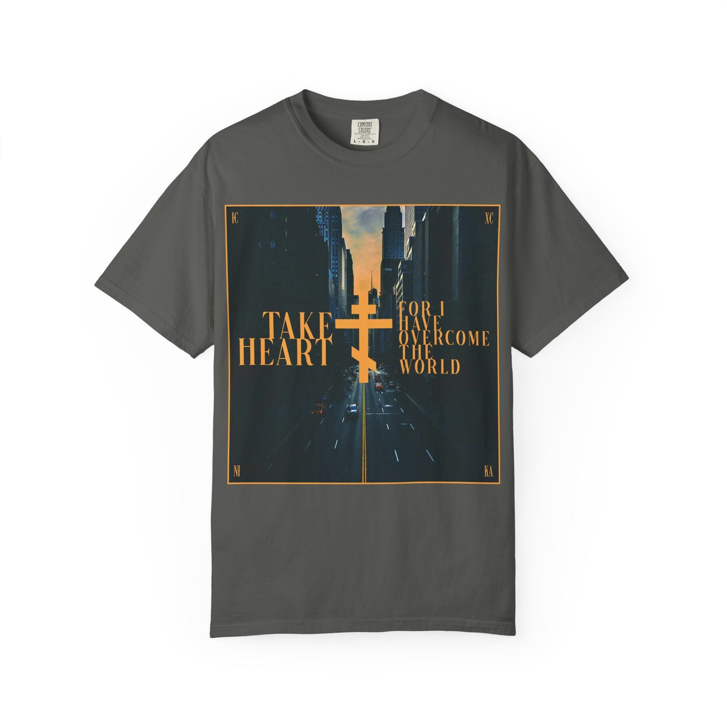 Pepper-colored heavyweight cotton unisex tee featuring the phrase "Take Heart, For I Have Overcome the World" (John 16:33) in yellow text over a modern city street scene—a reminder that sorrow is turned to joy for those who believe.