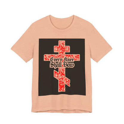 Peach unisex tee featuring a gold and red floral Orthodox cross with gothic "Every Knee Shall Bow" text (Isaiah 45:22-24, Phil 2:7-11), honoring Jesus Christ.