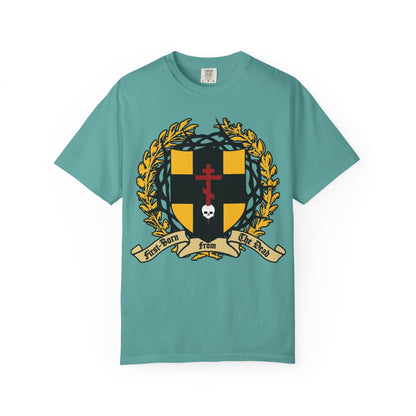 Seafoam heavyweight cotton unisex t-shirt featuring a black and gold heraldic shield with a crown of thorns, Orthodox cross piercing a skull, laurel wreath, and banner reading “First-Born from the Dead”—a bold design inspired by Colossians 1:18 and the story of redemption echoing Exodus.
