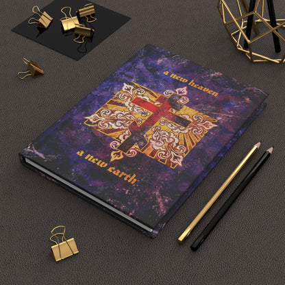 The "A New Heaven/A New Earth" Orthodox Christian Hardcover Journal, featuring a red Orthodox cross on a textured ornate background, sits on a desk surrounded by stationery.
