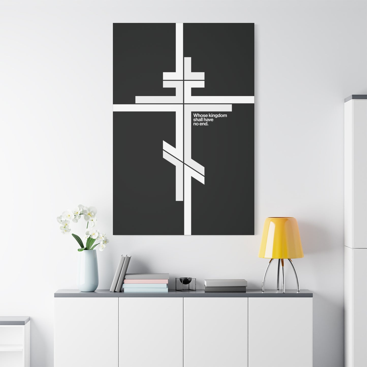 A modern room features "Whose Kingdom Shall Have No End"—a minimalist Orthodox Cross canvas inspired by Luke 1:32-33—above a cabinet with books, lamp, and flowers, uniting serene Christian meaning with contemporary decor.