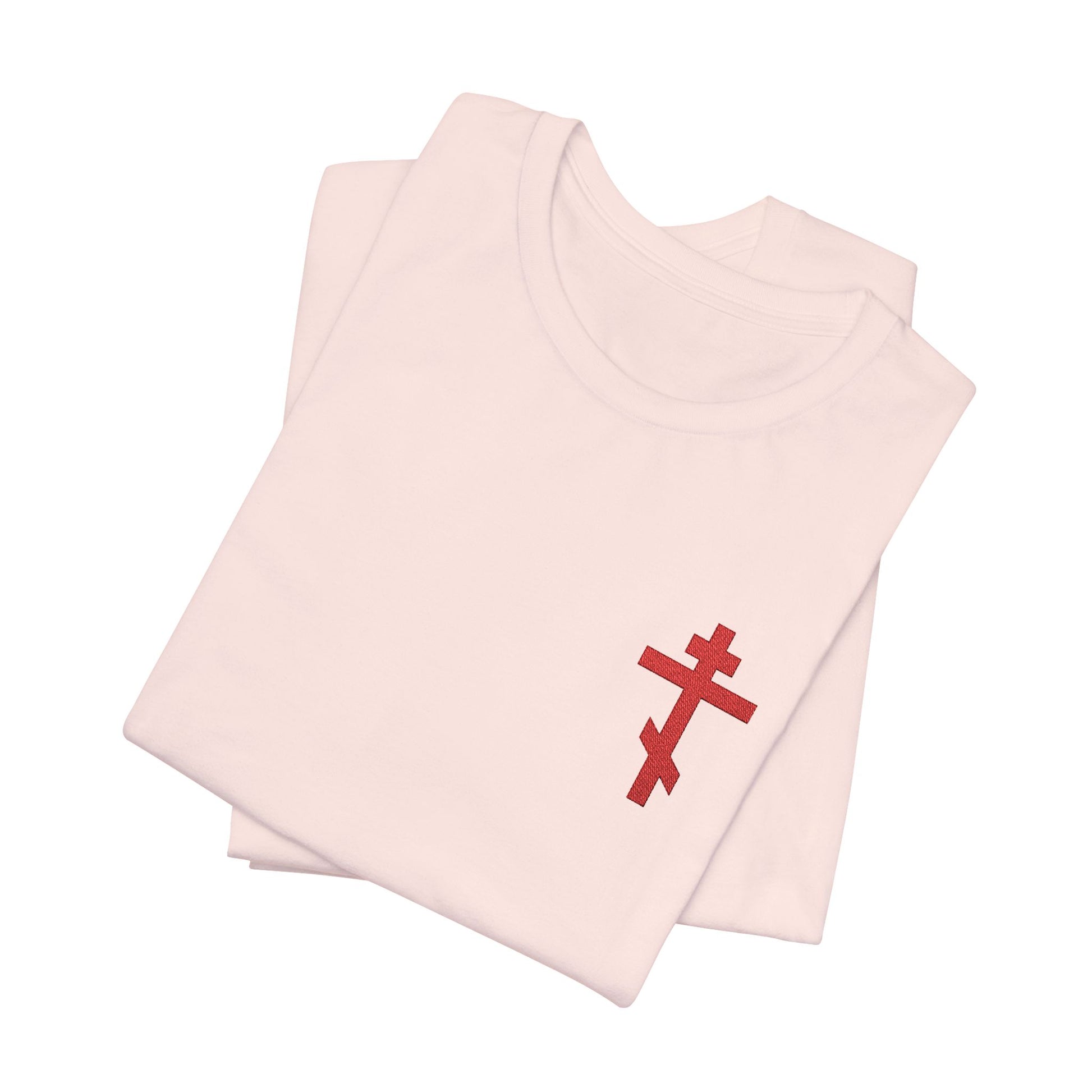 Two folded white t-shirts display a small red embroidered Orthodox cross, inspired by Galatians 6:14—"May I Never Boast Except in the Cross"—on this Christian cotton unisex tee.