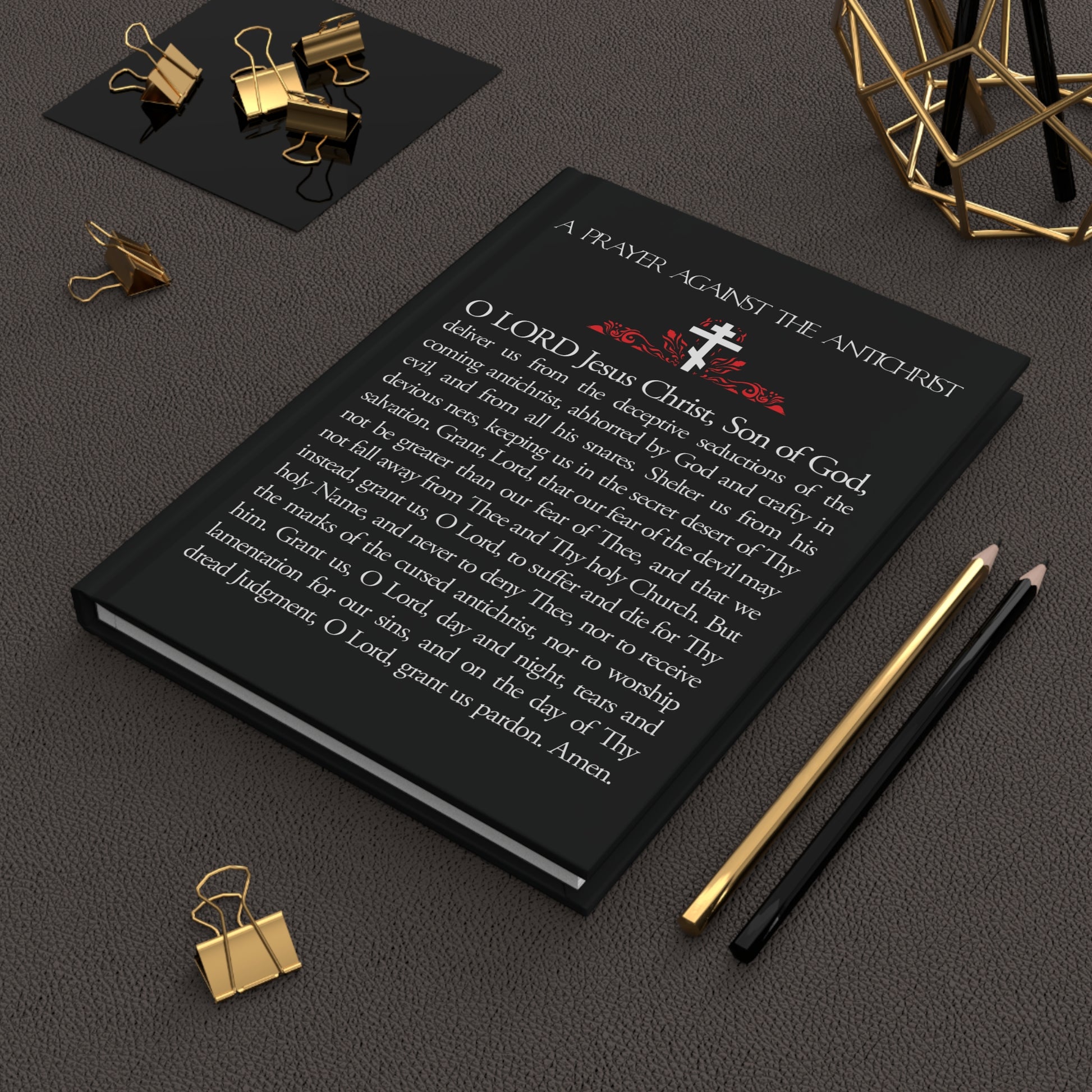 The “Prayer Against the Antichrist By Elder Anatoly the Younger of Optina | Christ is King | Book of Revelation” Orthodox Christian blank journal is pictured on a dark desk with gold stationery.