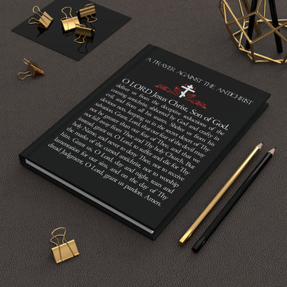 The “Prayer Against the Antichrist By Elder Anatoly the Younger of Optina | Christ is King | Book of Revelation” Orthodox Christian blank journal is pictured on a dark desk with gold stationery.