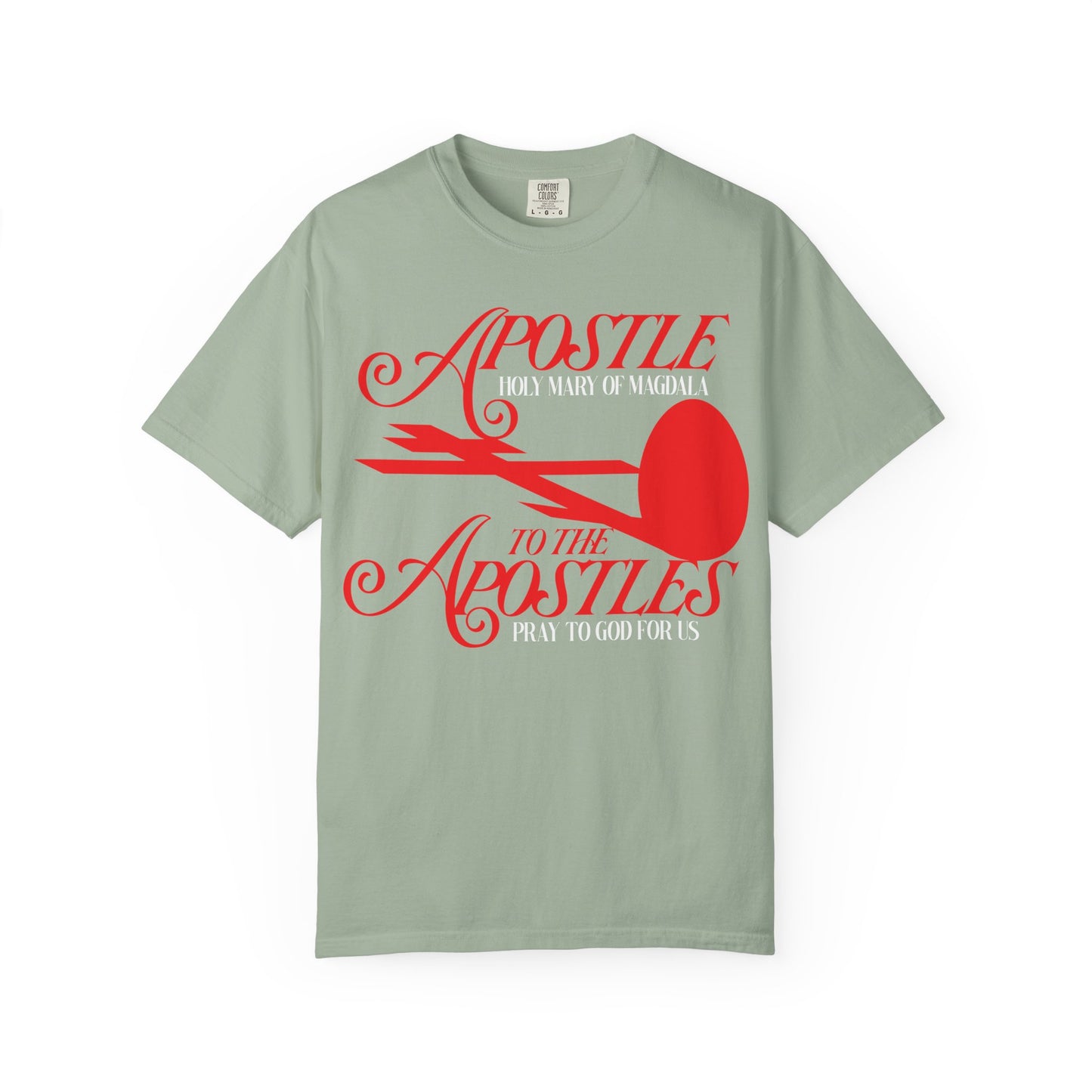 Bay-colored heavyweight cotton unisex tee featuring a red cross and red egg graphic with the text: “Apostle to the Apostles, Pray to God for Us”—honoring Saint Mary Magdalene, first witness to the Burial of the Lord and His Tomb.