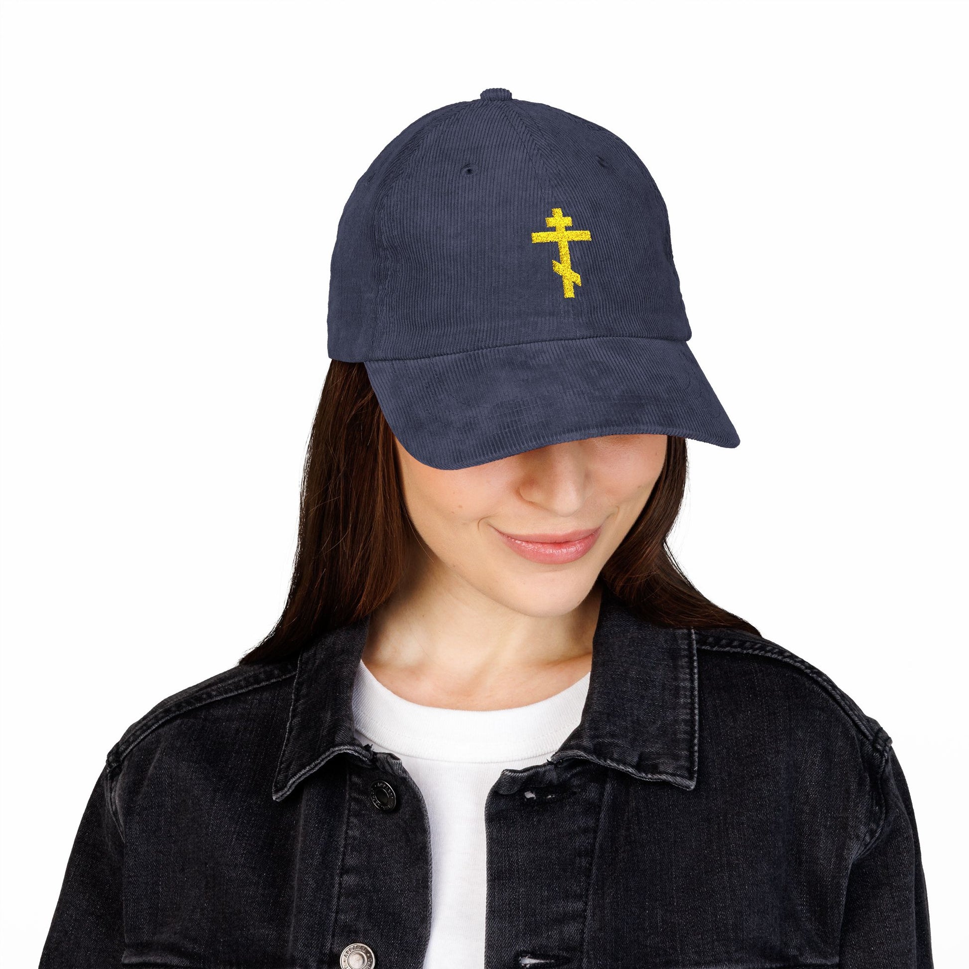 Woman wears the Simple Yellow Orthodox TriBar Cross Cotton Corduroy Cap—"Weapon of Unseen Warfare Which Makes Demons Tremble"—paired with a black denim jacket and white shirt.