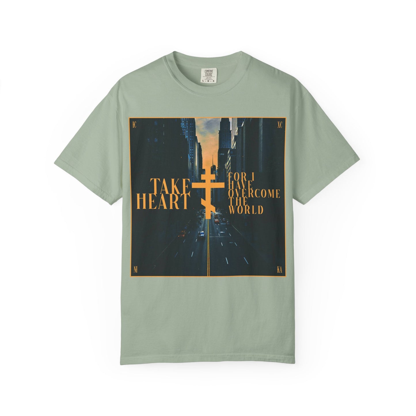 Bay-colored heavyweight cotton unisex tee featuring a modern city street scene, gold cross, and the message: Take Heart, For I Have Overcome the World (John 16:33)—a powerful reminder that sorrow is turned into joy for those who believe.