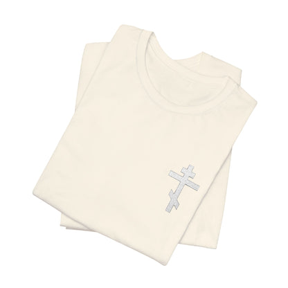 Two folded "White on Light" unisex tees in Airlume combed cotton, each with a small embroidered silver Orthodox cross on the chest. Lightweight retail fit, shown on a white background. Inspired by Gal 6:14: "May I Never Boast Except in the Cross.