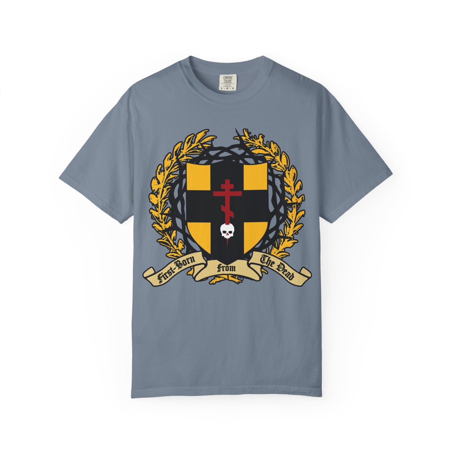 Blue Jean heavyweight cotton unisex t-shirt featuring a heraldic shield with an Orthodox cross piercing a skull, crowned with thorns and adorned by gold laurel. The design includes a banner reading “First Born From The Dead,” powerfully evoking the theme of redemption through His blood as expressed in Colossians 1:18.